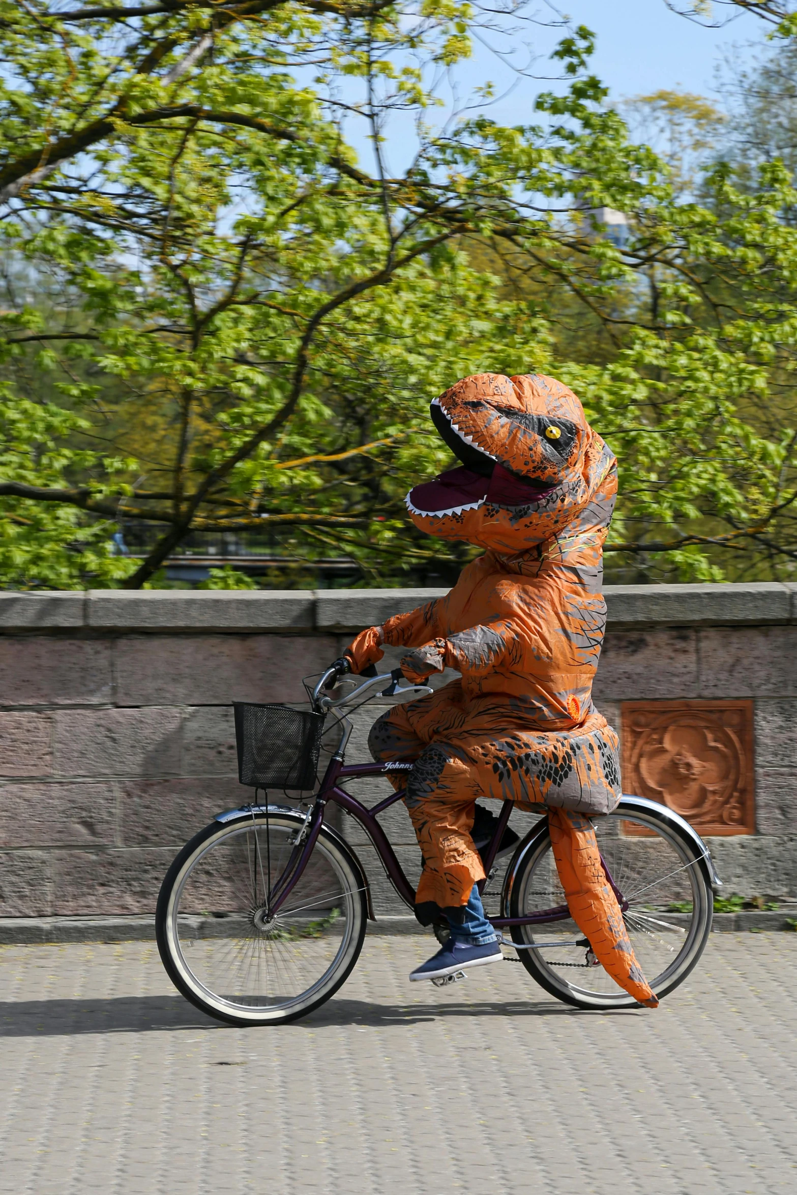 a man is dressed up as a dinosaur on a bicycle