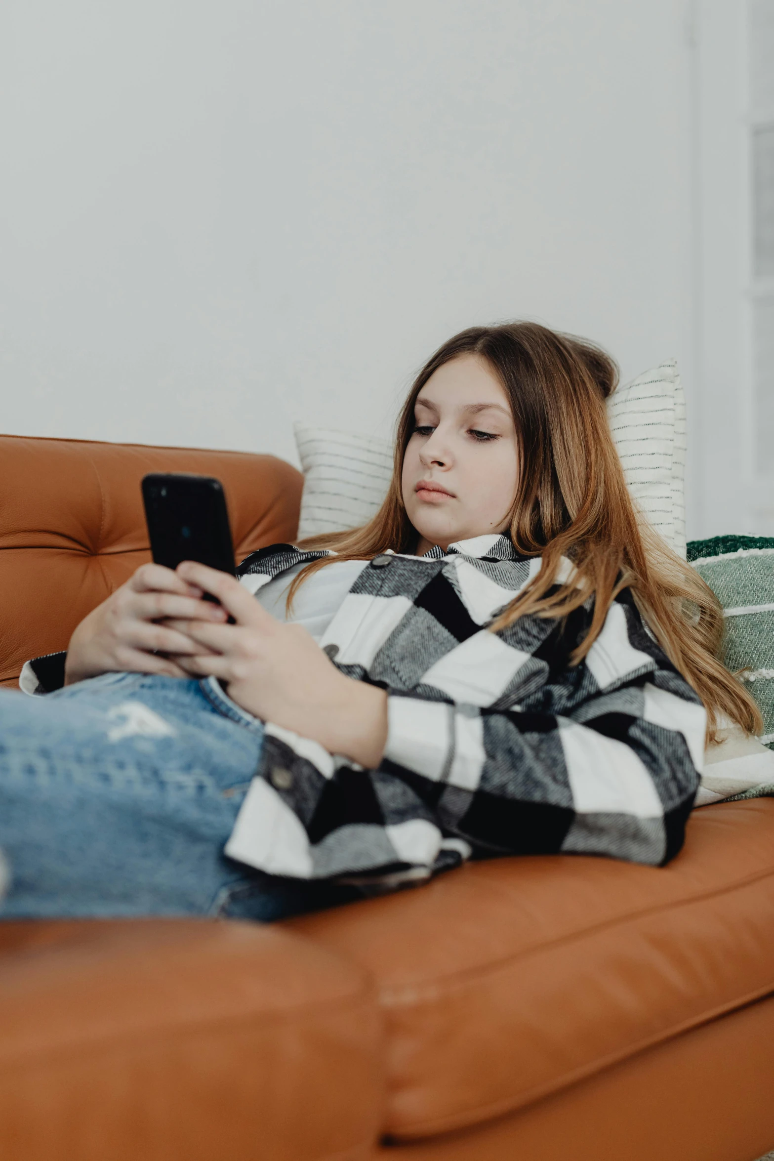 a woman laying on a couch using a cell phone, trending on pexels, portrait of white teenage girl, looking serious, really long, 2019 trending photo