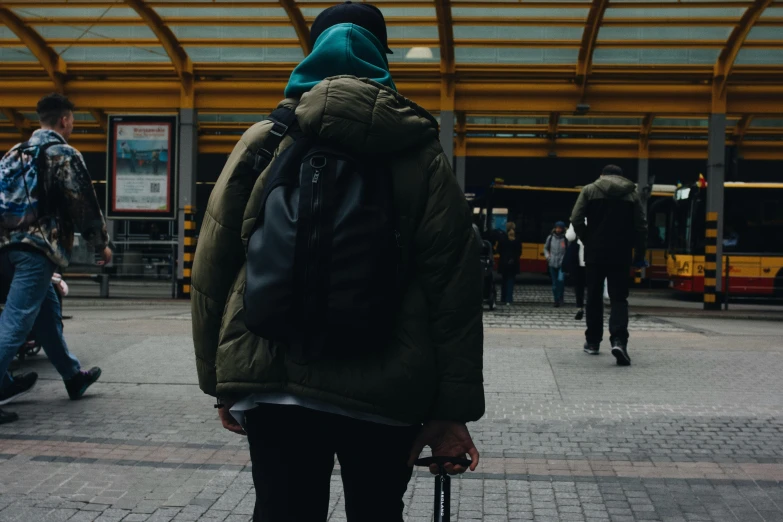 a man wearing a backpack standing on a public walkway