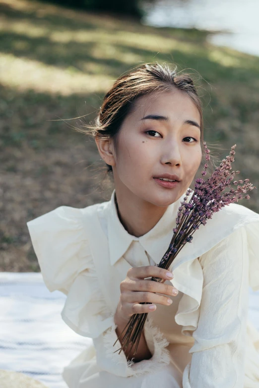 a woman sitting on a blanket holding a bunch of flowers, inspired by Kim Tschang Yeul, trending on pexels, wearing white shirt, kiko mizuhara, dried flowers, closeup portrait