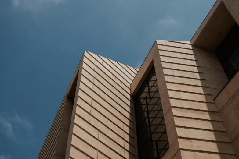 a tall building with a clock on top of it, an album cover, inspired by David Chipperfield, unsplash, brutalism, rammed earth courtyard, close up shot from the side, light - brown wall, diagonal lines