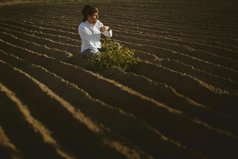 a woman sitting in the middle of a field, by Elsa Bleda, land art, next to a plant, chilean, farmer, profile image