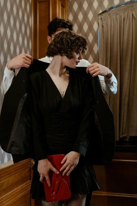 a woman standing next to a man in front of a mirror, inspired by Nan Goldin, renaissance, subject detail: wearing a suit, dressed as a judge's robes, timothee chalamet, ( ( theatrical ) )