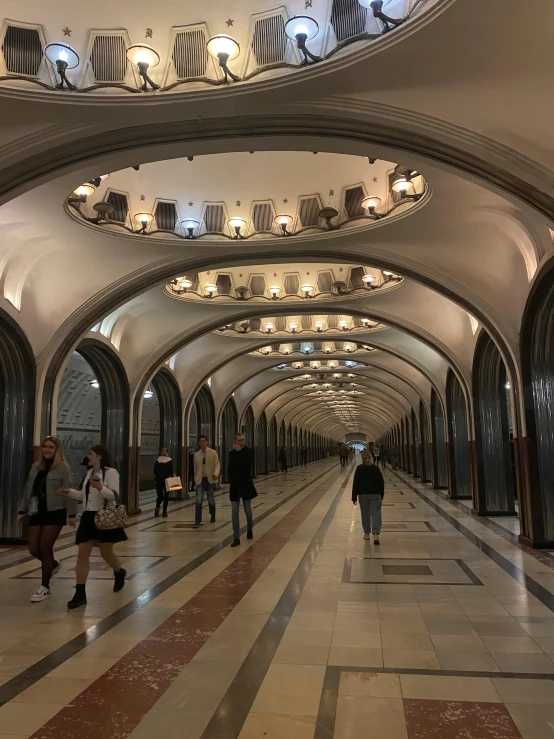 a group of people walking down a long hallway, art nouveau, moscow metro, steel archways, 🚿🗝📝, profile image