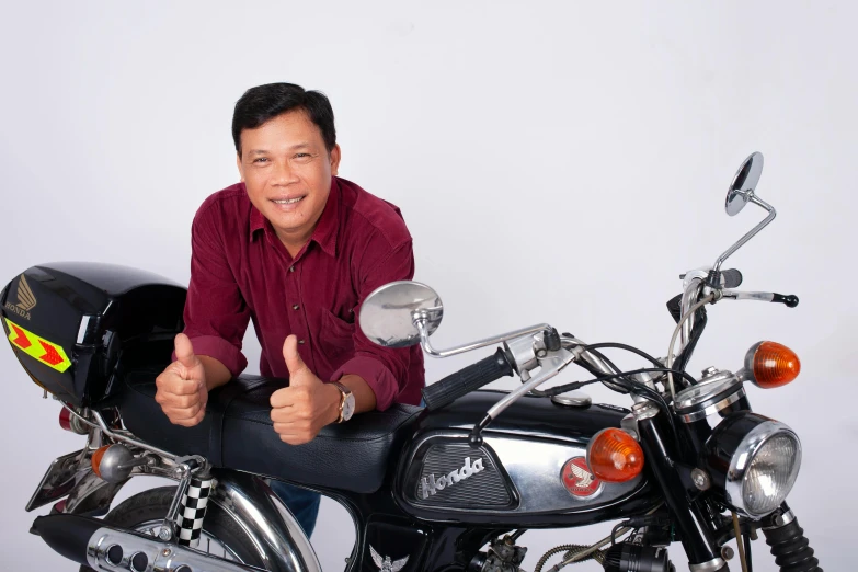 a person that is giving a thumbs up sitting on a motorcycle
