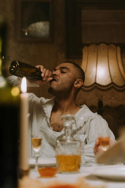 a man drinking beer while sitting at a dinner table