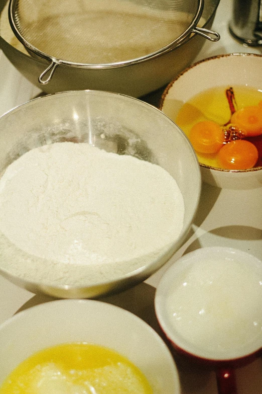 a table topped with bowls and bowls of food, covered in white flour, upclose, in the kitchen, kek