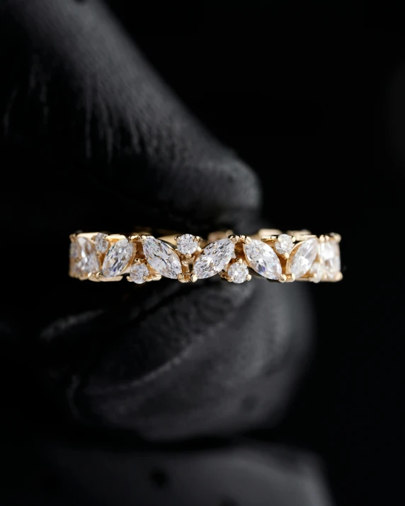 a close up of a person's hand holding a diamond ring, inspired by L. A. Ring, hurufiyya, on black background, gold flaked flowers, marquis cut, thumbnail