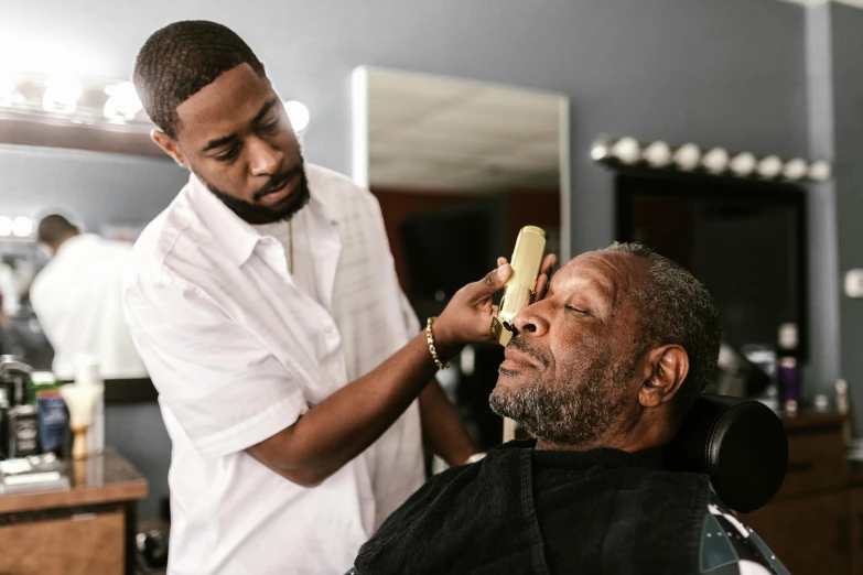 a man getting his hair cut by a barber, by Dan Frazier, pexels contest winner, morgan freeman as gordon freeman, thick black beard, shaved temple, pronounced facial contouring