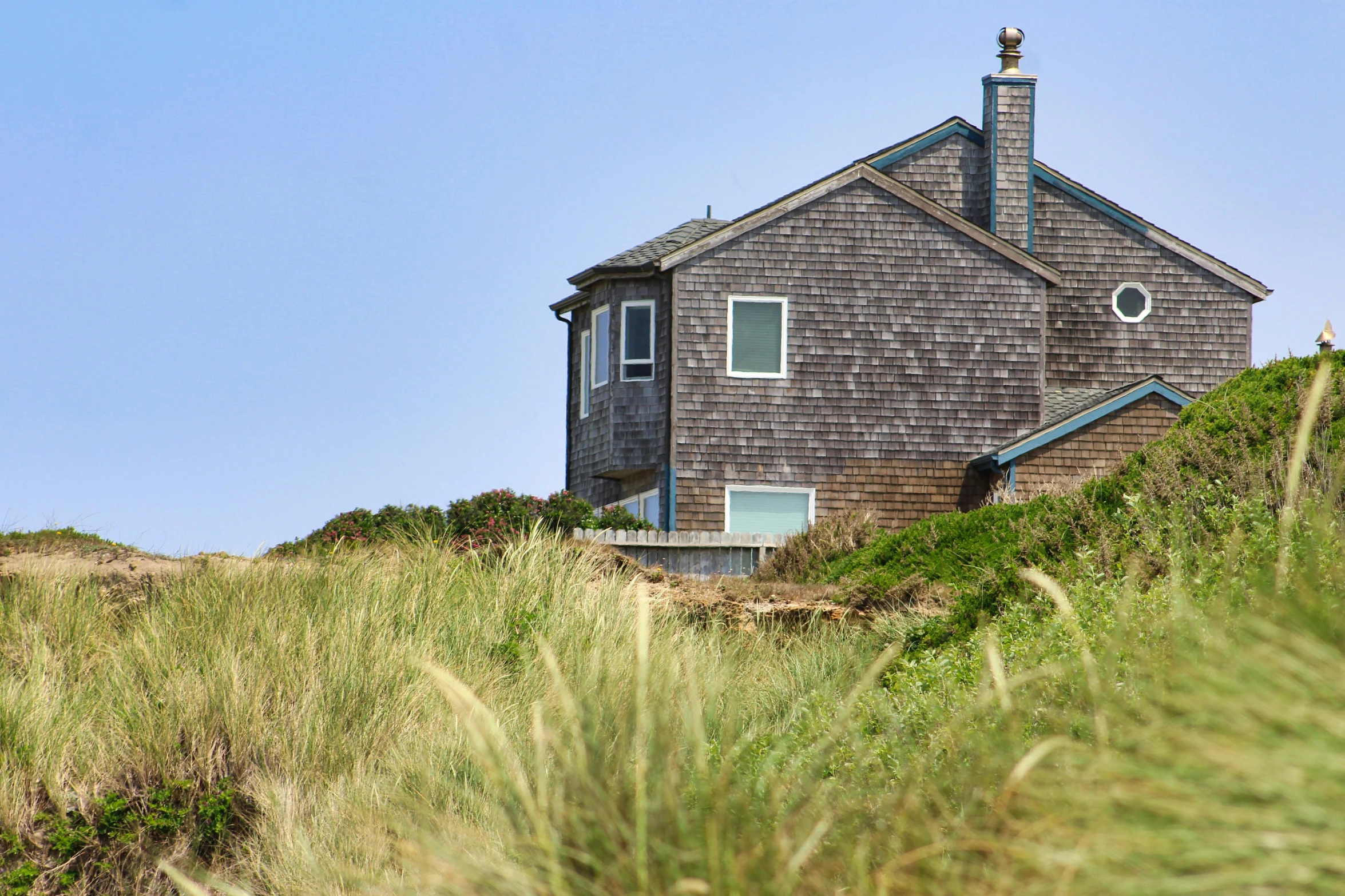 a small house is on the shore of a beach