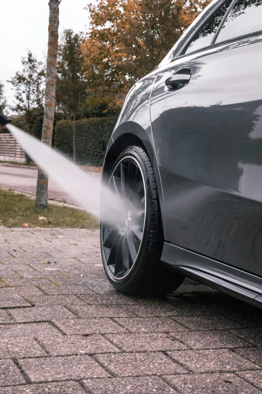 the front wheel is spraying water onto a grey car