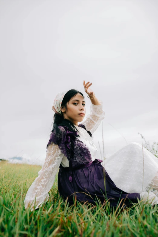 a lady is sitting in the grass wearing a frock