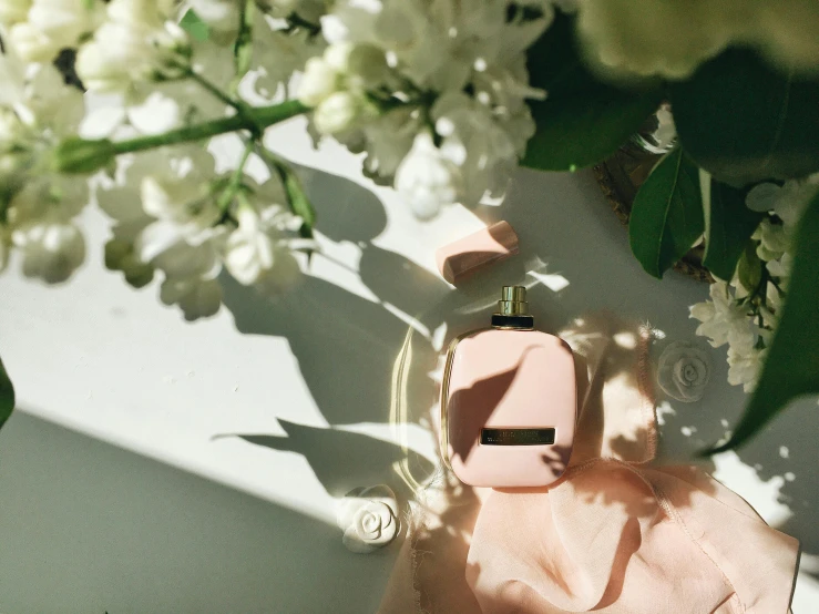 some flowers and perfume bottles on top of a pink blanket