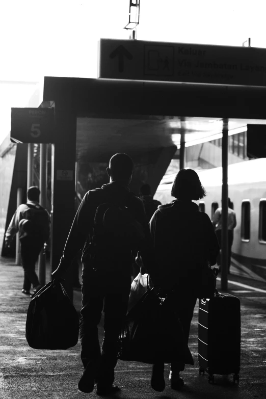 a black and white photo of people at a train station, flickr, sunset!, couple, flight, luggage