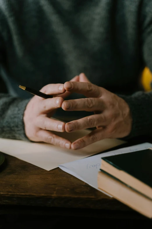 the man is holding a pen and writing on paper