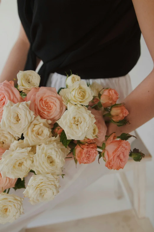an arrangement of white and peach flowers in the hands