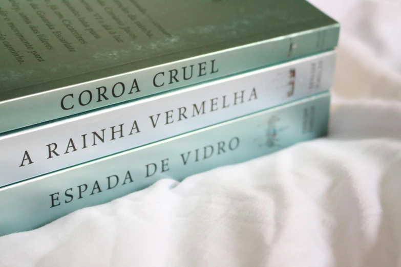 a stack of books sitting on top of a bed, by Victoria Francés, sea green color theme, scoia'tael), the three moiras, henrique alvim corrêa