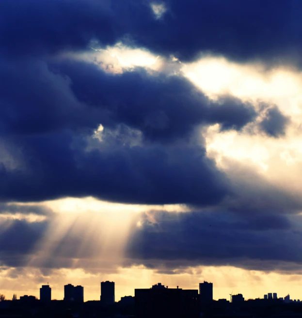 the sun shines through the clouds over a city, minimalism, brooding clouds', photograph, dramatic”