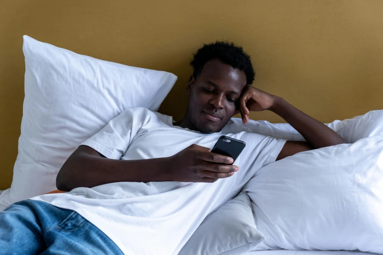 a man is laying in bed while using his cellphone