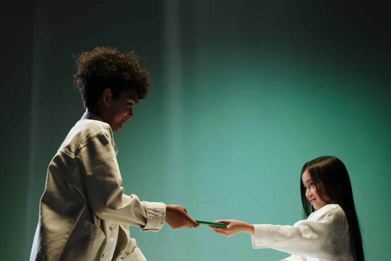 a couple of people standing next to each other on a stage, pexels contest winner, interactive art, green robe, white belt, kids playing, reaching out to each other