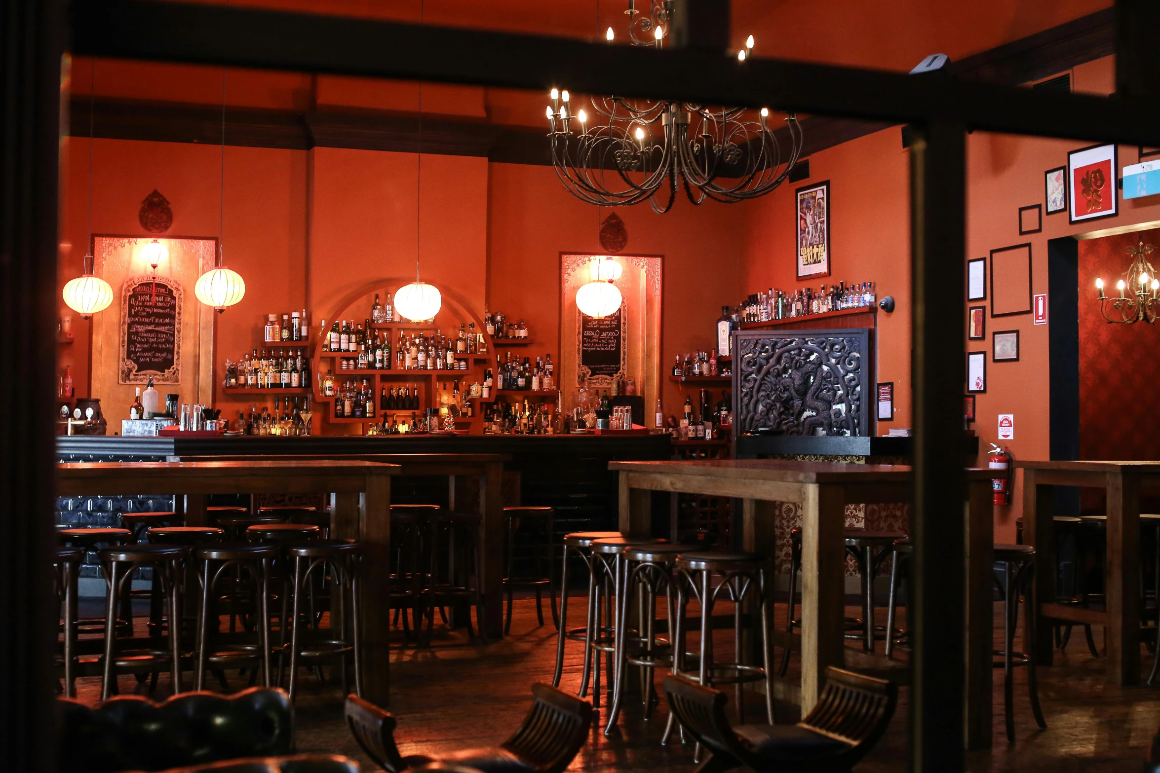 a bar with chandeliers, wooden tables and chairs