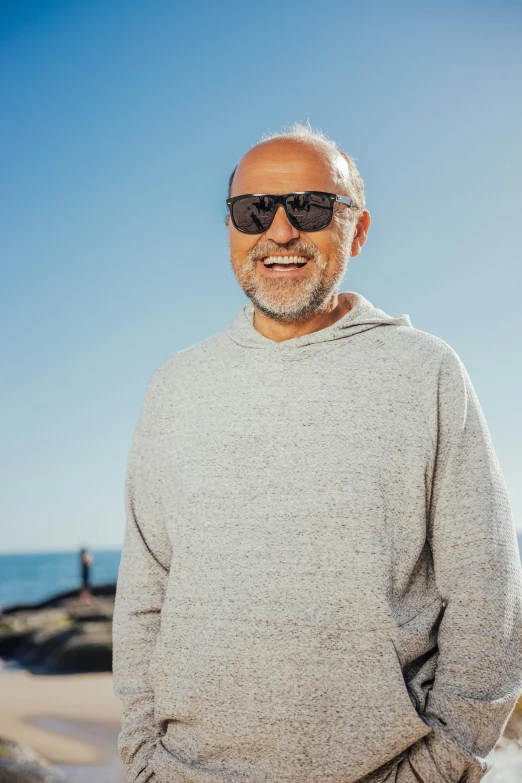 a smiling older man wearing sunglasses on the beach