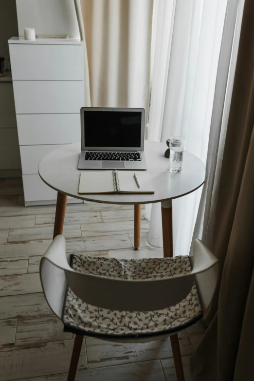 a chair in front of the table with a laptop on it