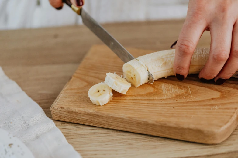 a person cutting a banana on a cutting board, trending on pexels, holding a wooden staff, white, low detail, rectangle