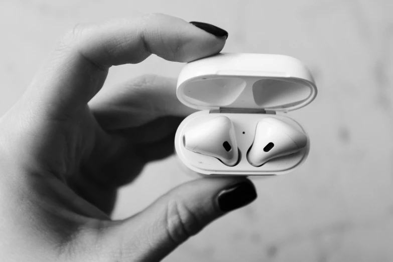 a person holding a pair of airpods in their hand, a black and white photo, by Emma Andijewska, pexels, white plastic, hyperdetailed!!, square, dream