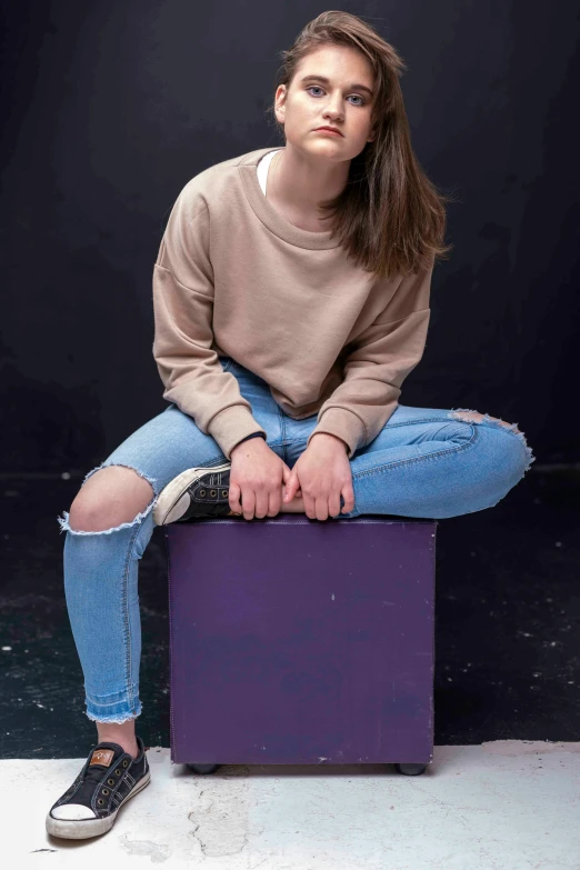 a woman sitting on top of a purple box