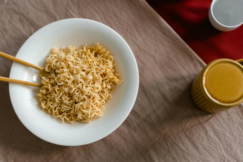 a bowl of noodles with chopsticks on a table, by Carey Morris, pexels contest winner, cheerios, yellow, soft shade, 4l