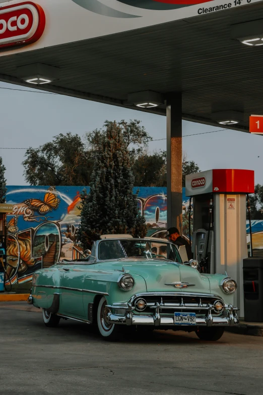 an old fashioned chevrolet with an oil pump at a station