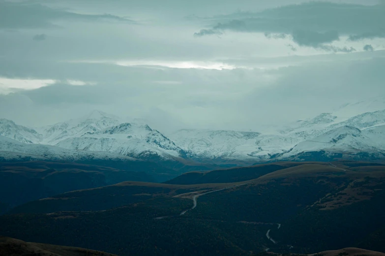 view of snow capped mountains and highway taken from a hill