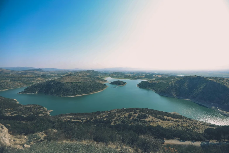 water is on the side of an area with green trees and mountains