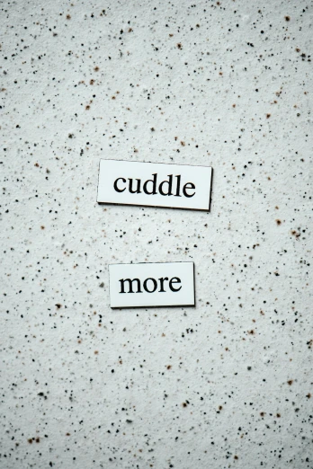 two pieces of paper that say cuddle and more, magnetic, definition, on a pale background, in a chill position