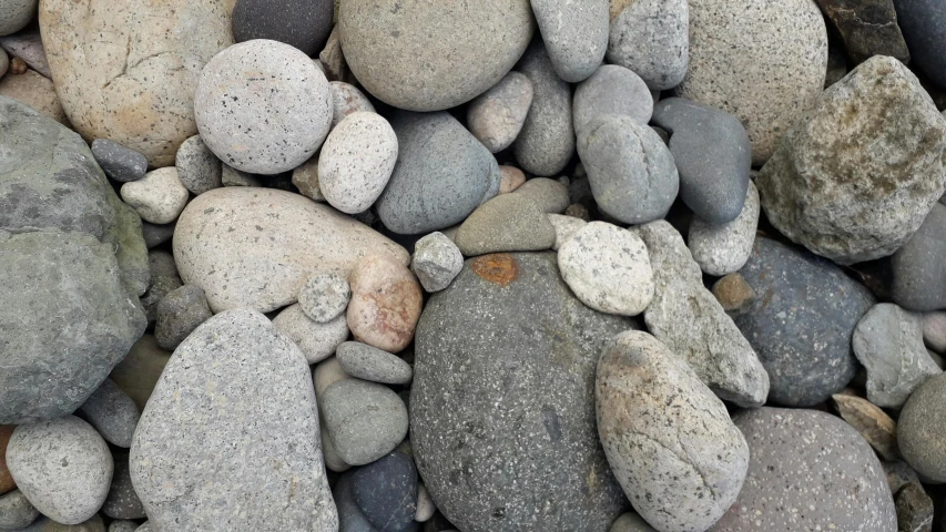 a pile of rocks sitting on top of a beach, an album cover, inspired by Vija Celmins, unsplash, smooth rounded shapes, grey, multicoloured, small