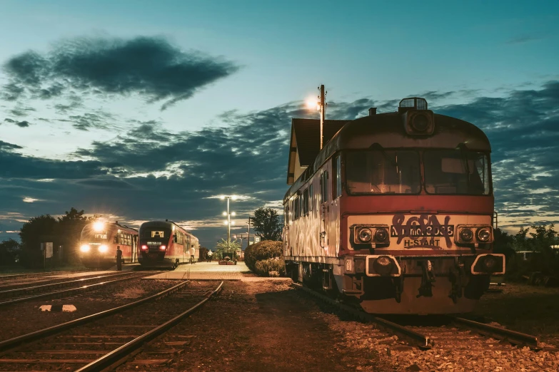 a couple of trains that are on some tracks, by Lee Loughridge, unsplash contest winner, fantastic realism, night time australian outback, dieselpunk railway station, profile image, late summer evening