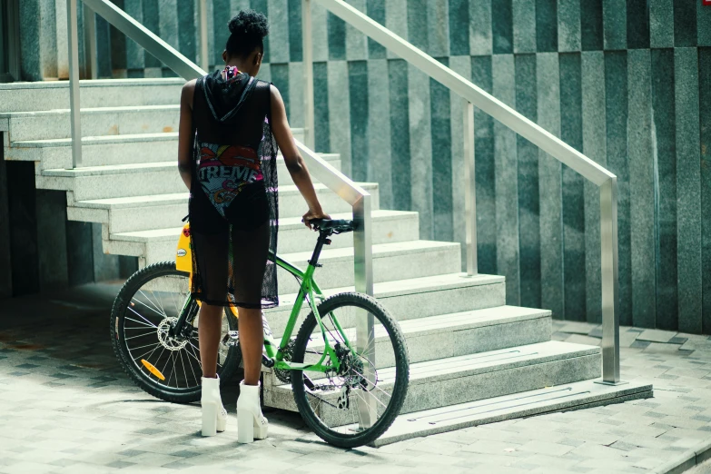 a woman that is standing next to a bike, pexels contest winner, green and black, full growth from the back, student, maria borges