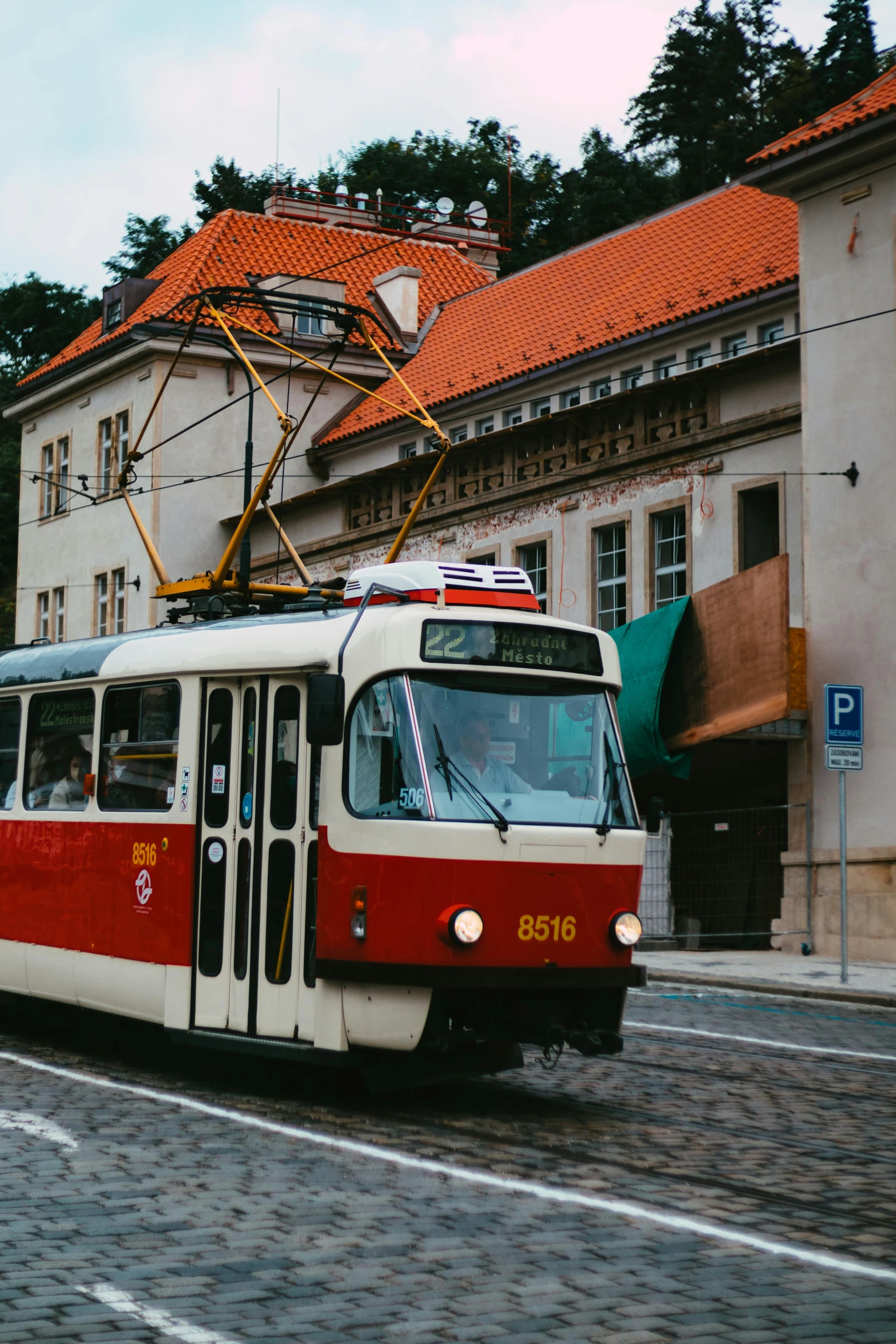 a red and white train traveling down a street, by Matija Jama, pexels contest winner, preserved historical, square, slightly tanned, gif