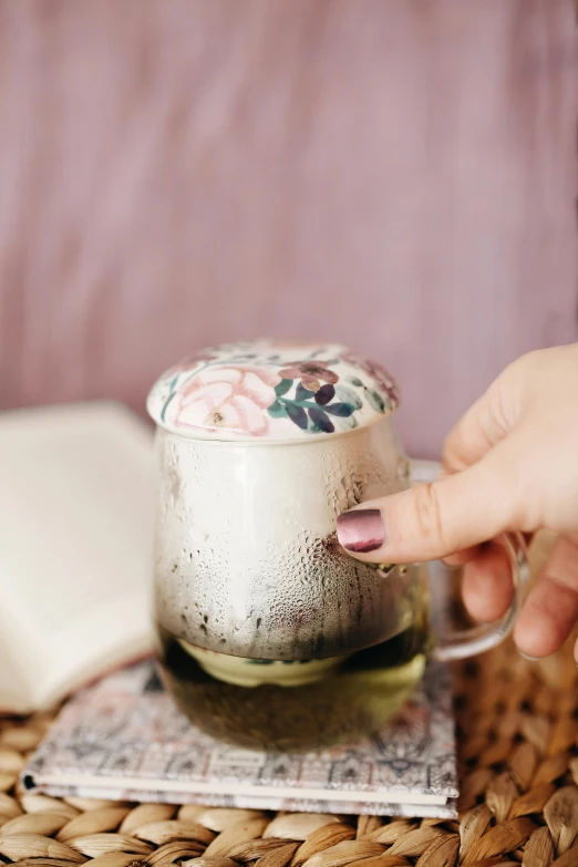 a close up of a person holding a cup of coffee, floral patterned skin, glass cover, muted pastels, potion