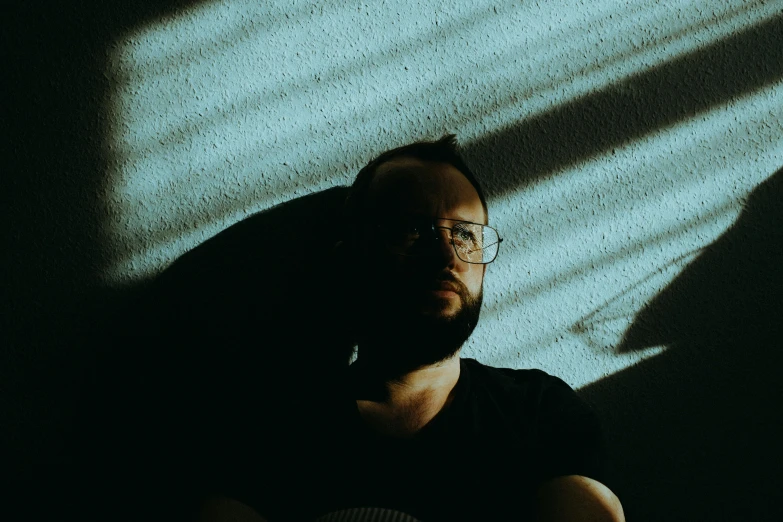 a man with glasses sitting in front of a wall, pexels contest winner, ambient teal light, softly shadowed, sam hyde, avatar image