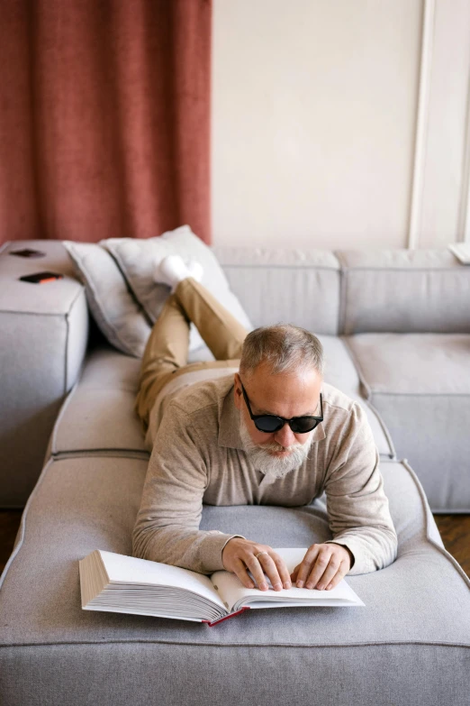 a man laying on a couch reading a book, inspired by Carl Gustaf Pilo, trending on unsplash, implanted sunglasses, an oldman, profile image, cardboard