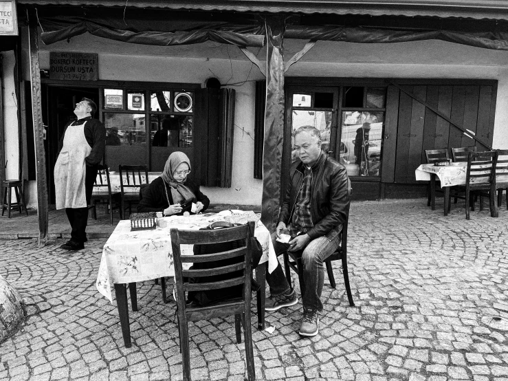 two men are sitting at an outdoor table