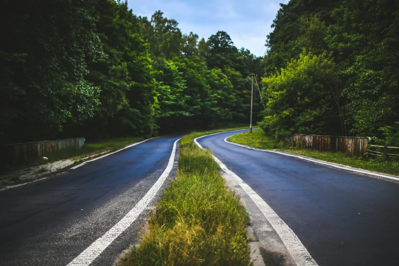 an empty road in the middle of a forest, by Adam Szentpétery, unsplash, 2 5 6 x 2 5 6 pixels, green lines, asphalt and metal, split near the left