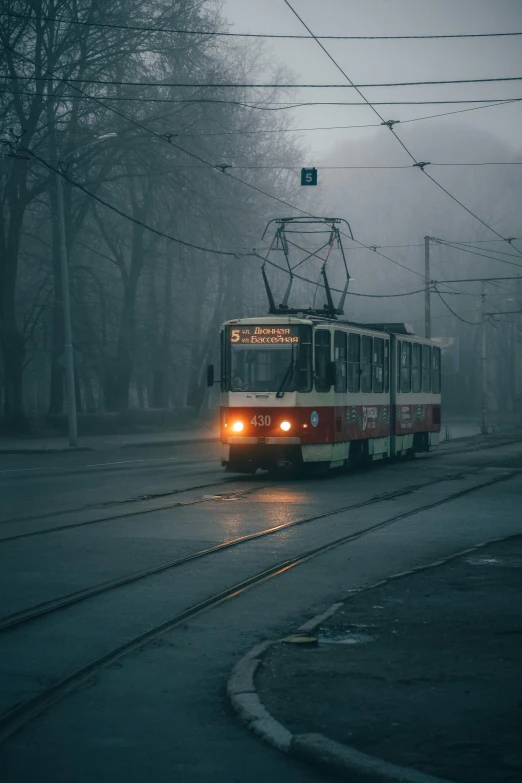 a red and white tram traveling down a street, by Adam Marczyński, pexels contest winner, socialist realism, misty ominous atmosphere, square, freezing, grey