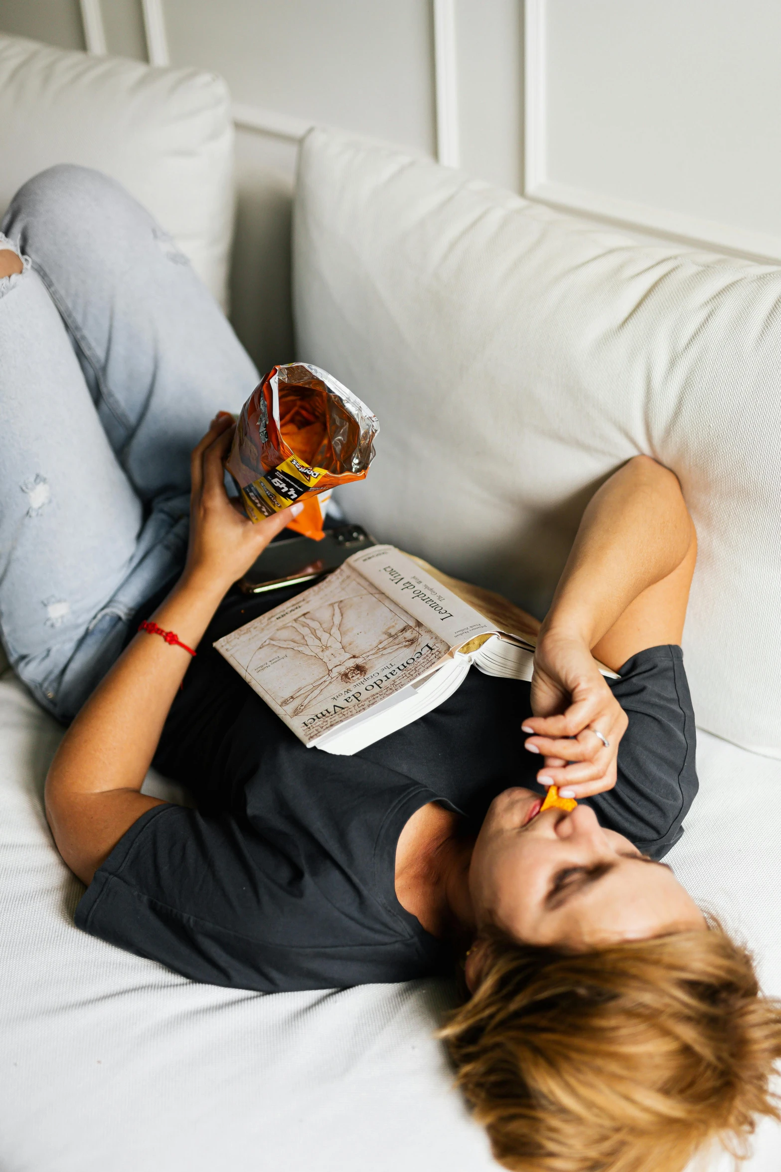 a person lays down on a couch and reads