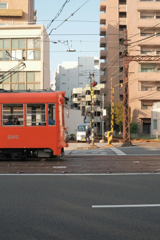 a red trolley car going down the street next to tall buildings