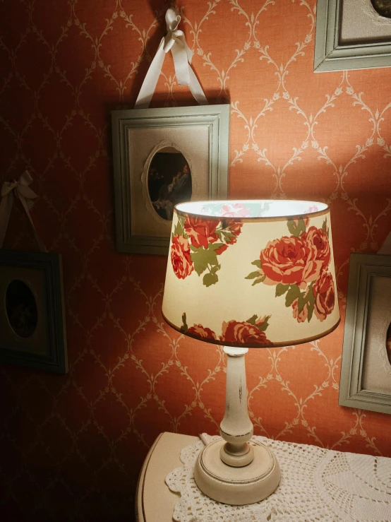 a lamp sitting on a table under three pictures