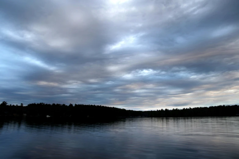 dark, cloud filled skies are seen over calm water