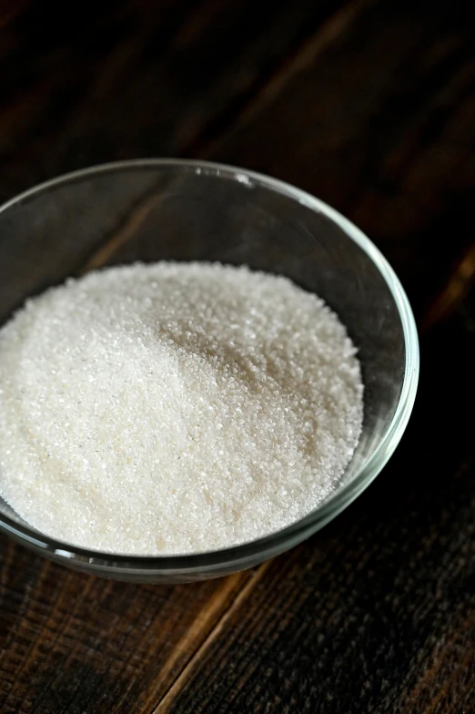 a bowl of sugar sitting on top of a wooden table, up-close, detailed product image, bubbly, crust